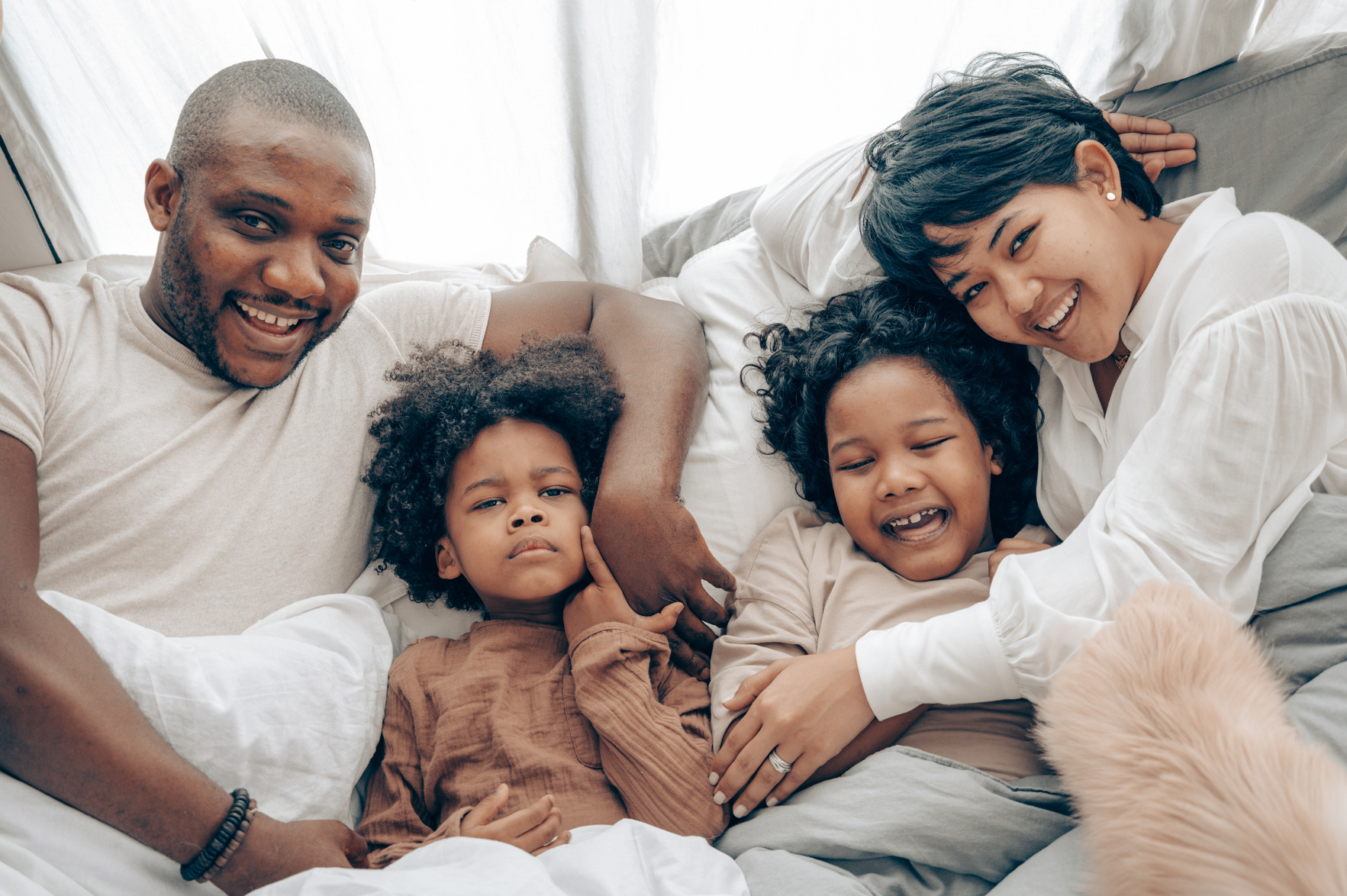 Happy diverse family resting on bed in morning