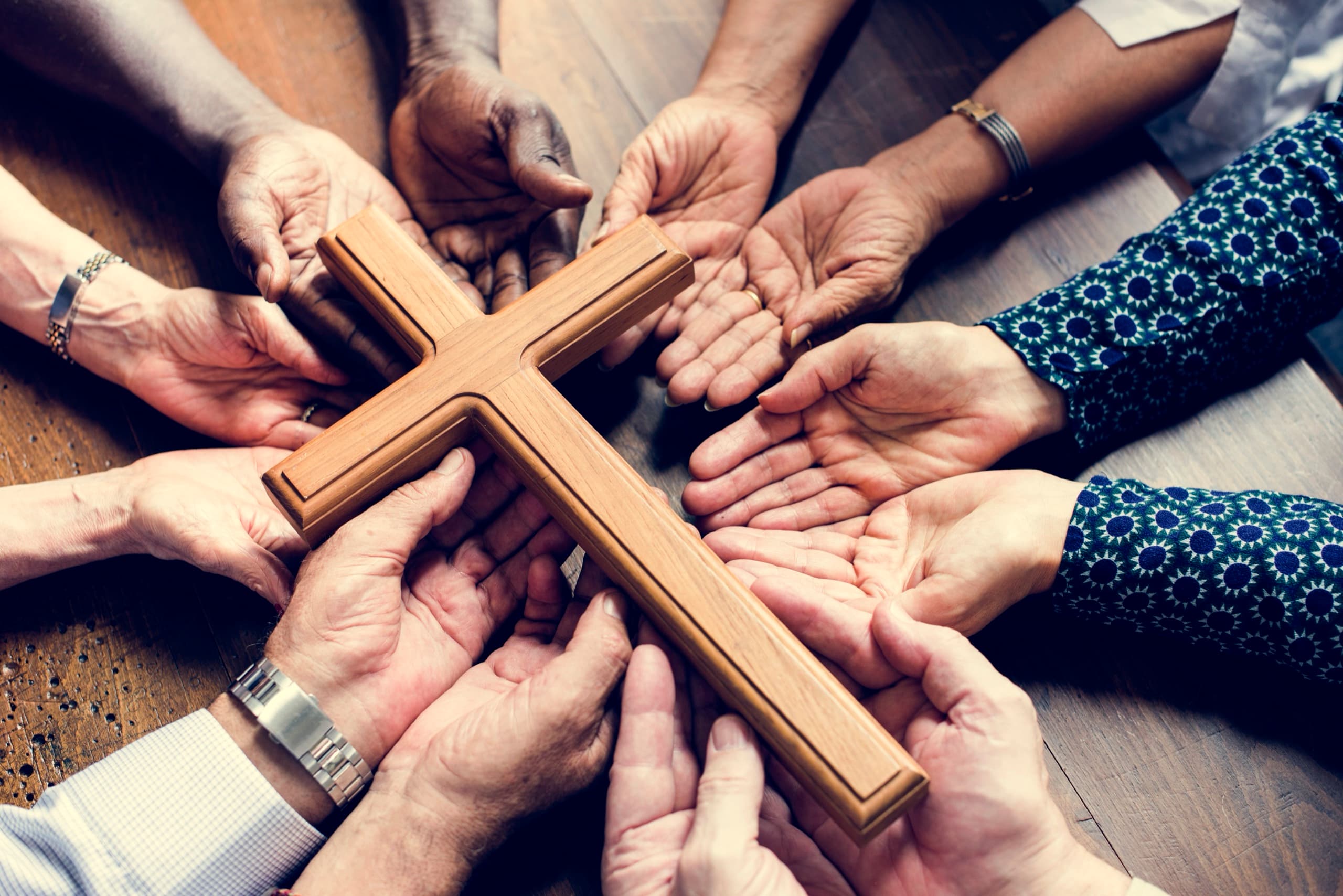 People joining together around a wooden cross